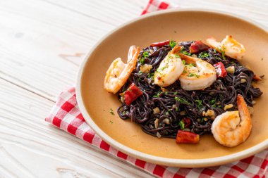 Sarımsaklı ve karidesli kızarmış siyah spagetti.