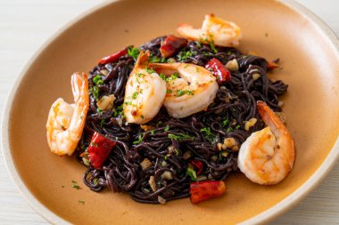 Sarımsaklı ve karidesli kızarmış siyah spagetti.
