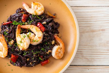 Sarımsaklı ve karidesli kızarmış siyah spagetti.