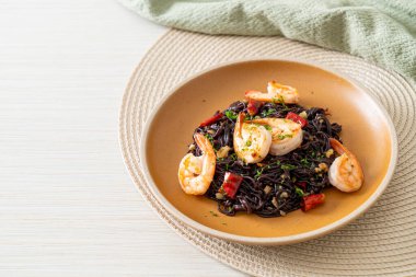 Sarımsaklı ve karidesli kızarmış siyah spagetti.