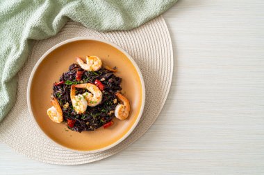 Sarımsaklı ve karidesli kızarmış siyah spagetti.