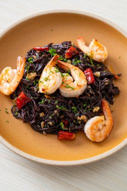 Sarımsaklı ve karidesli kızarmış siyah spagetti.