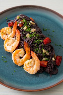 Sarımsaklı ve karidesli kızarmış siyah spagetti.