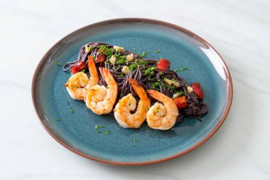 Sarımsaklı ve karidesli kızarmış siyah spagetti.