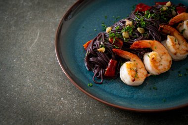 Sarımsaklı ve karidesli kızarmış siyah spagetti.