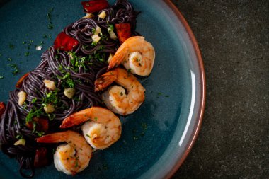 Sarımsaklı ve karidesli kızarmış siyah spagetti.