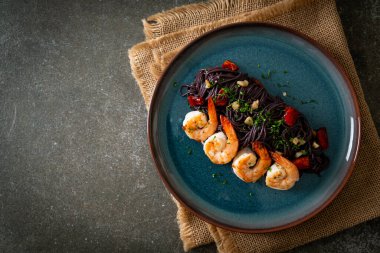 Sarımsaklı ve karidesli kızarmış siyah spagetti.