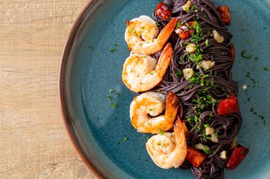 Sarımsaklı ve karidesli kızarmış siyah spagetti.