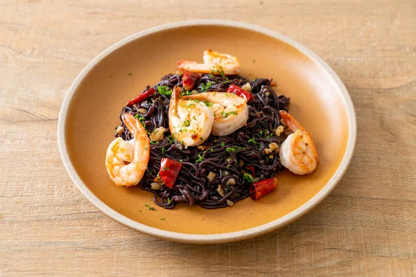 Sarımsaklı ve karidesli kızarmış siyah spagetti.