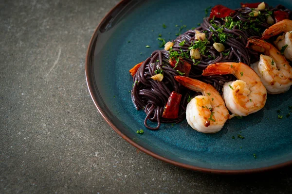 Sarımsaklı ve karidesli kızarmış siyah spagetti.