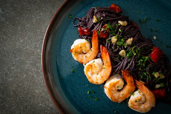 Sarımsaklı ve karidesli kızarmış siyah spagetti.