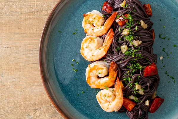 Sarımsaklı ve karidesli kızarmış siyah spagetti.