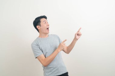 Beyaz arka planda eli işaret eden ya da sunan genç Asyalı adam portresi