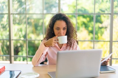 Latin kadın kahve fincanıyla çalışıyor.