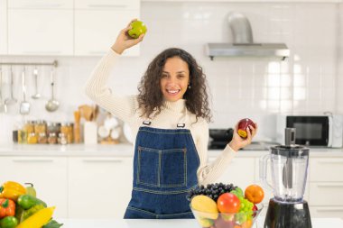 Latin kadın, vejetaryen yemeği için mutfakta meyve suyu yapıyor.