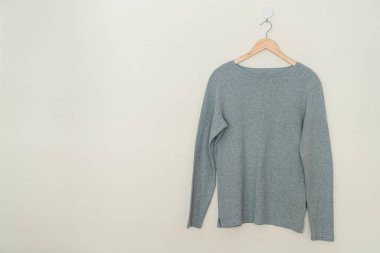 grey t-shirt hanging with wood hanger on wall