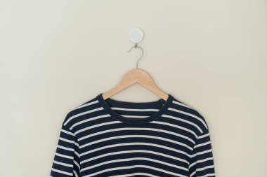 navy t-shirt hanging with wood hanger on wall