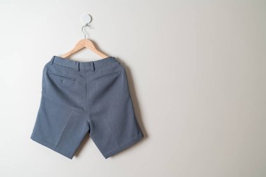 Kısa pantolon duvarda ahşap bir askıyla asılı.