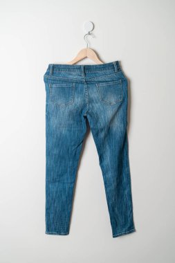 Pantolonlar duvarda ahşap bir askıyla asılı.