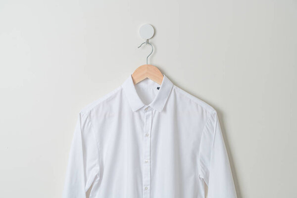 hanging white shirt with wood hanger on wall
