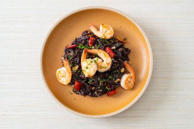 Sarımsaklı ve karidesli kızarmış siyah spagetti.