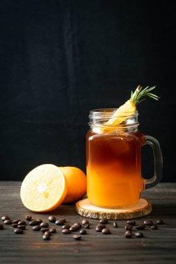 Bir bardak buzlu americano sade kahve ve biberiye ve tarçınla süslenmiş portakal ve limon suyu.