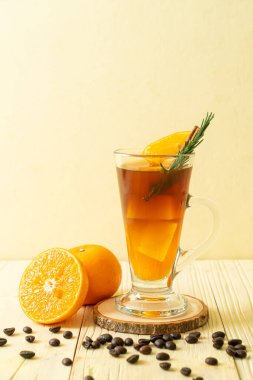 Bir bardak buzlu americano sade kahve ve biberiye ve tarçınla süslenmiş portakal ve limon suyu.