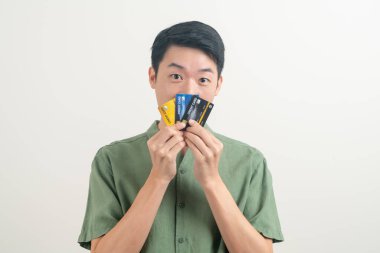 Beyaz arka planda kredi kartı tutan genç Asyalı adam portresi