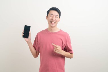 Genç Asyalı adam beyaz arka planda mutlu yüzlü akıllı telefon ve cep telefonu kullanıyor veya konuşuyor