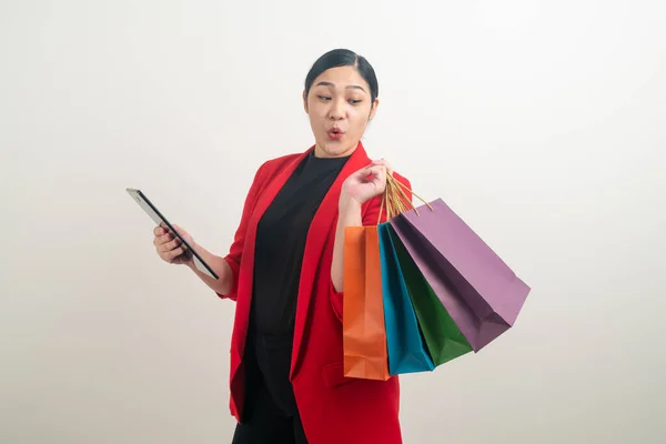 白い背景を持つ手にショッピングバッグやタブレットを持つアジアの女性 — ストック写真
