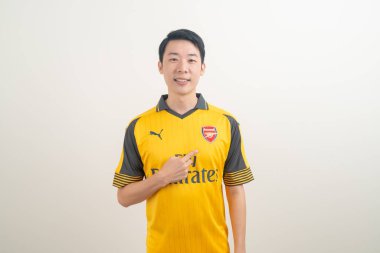 Bangkok, THAILAND - 27 Kasım 2021: beyaz arka planda Arsenal tişörtü giyen genç Asyalı. Arsenal, Londra 'nın en ünlü futbol kulübüdür..