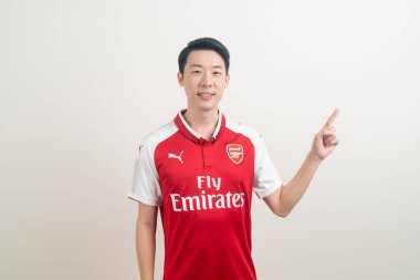 Bangkok, THAILAND - 27 Kasım 2021: beyaz arka planda Arsenal tişörtü giyen genç Asyalı. Arsenal, Londra 'nın en ünlü futbol kulübüdür..