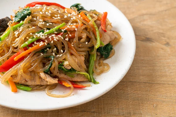 白ゴマの上に野菜と豚肉をのせた日本風または炒め物の韓国の春雨麺 韓国の伝統料理 — ストック写真