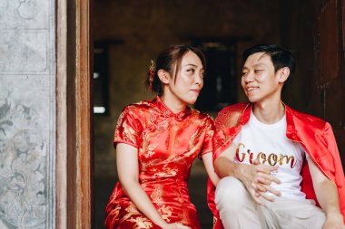 Mutlu genç Asyalı çiftler geleneksel Çin elbiseleriyle sevişir. Kırmızı, geleneksel bayramın ana rengidir. Buna Çin 'de düğün de dahil..