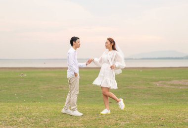 Gelin ve damat kıyafetli mutlu genç Asyalı çift evlenmeye ve evlenmeye hazır.