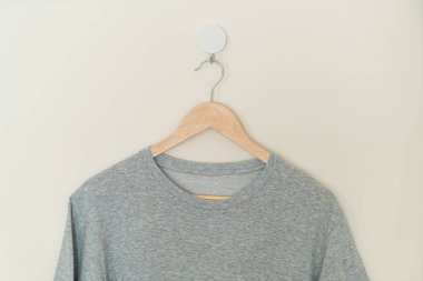 grey t-shirt hanging with wood hanger on wall