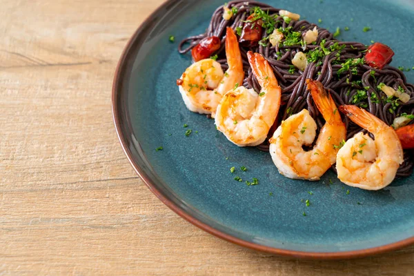 Sarımsaklı ve karidesli kızarmış siyah spagetti.