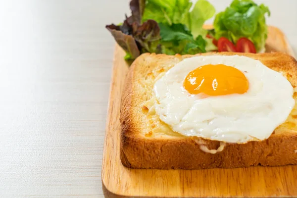 homemade bread toasted with cheese and fried egg on top with vegetable salad for breakfast