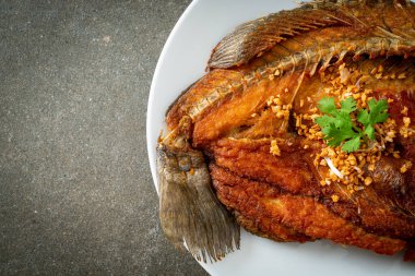 Tabakta sarımsaklı kızarmış deniz levreği balığı.