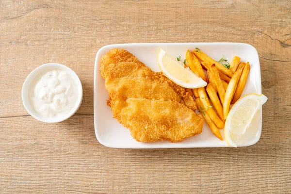 fish and chips - fried fish fillet with potatoes chips and lemon on white plate