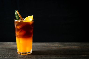 Bir bardak buzlu americano sade kahve ve biberiye ve tarçınla süslenmiş portakal ve limon suyu.