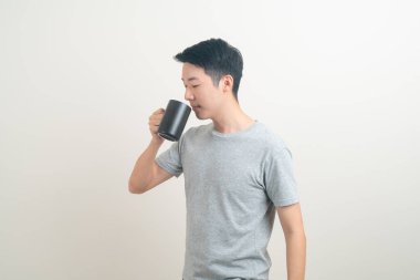 Genç Asyalı adam elinde kahve fincanı beyaz arka planda gülümseyen yüzüyle