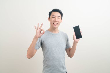 Beyaz arka planda akıllı telefon ve cep telefonu kullanan ya da konuşan genç Asyalı adam