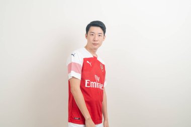 Bangkok, THAILAND - 27 Kasım 2021: beyaz arka planda Arsenal tişörtü giyen genç Asyalı. Arsenal, Londra 'nın en ünlü futbol kulübüdür..