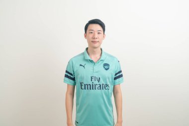 Bangkok, THAILAND - 27 Kasım 2021: beyaz arka planda Arsenal tişörtü giyen genç Asyalı. Arsenal, Londra 'nın en ünlü futbol kulübüdür..