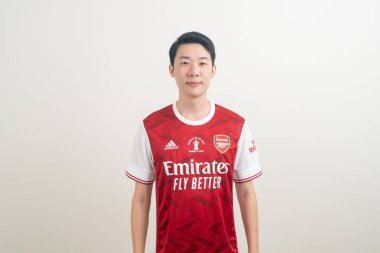 Bangkok, THAILAND - 27 Kasım 2021: beyaz arka planda Arsenal tişörtü giyen genç Asyalı. Arsenal, Londra 'nın en ünlü futbol kulübüdür..