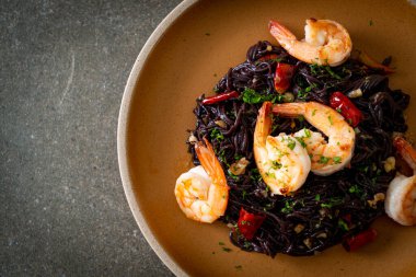 Sarımsaklı ve karidesli kızarmış siyah spagetti.