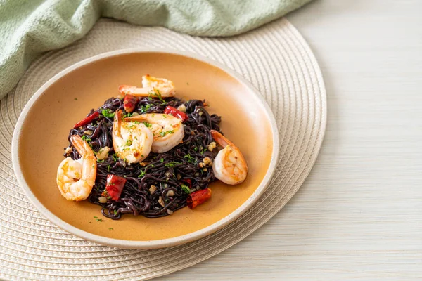 Sarımsaklı ve karidesli kızarmış siyah spagetti.