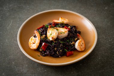 Sarımsaklı ve karidesli kızarmış siyah spagetti.