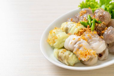 Şeffaf toplara Saku Sai Moo ya da Buharlı Tapioca Köfte Topları ve (Kow Griep Pag Mor) Domuz Buharlı Pirinç Paketleri ya da Haşlanmış Pirinç Kabuklu Mantı denir.